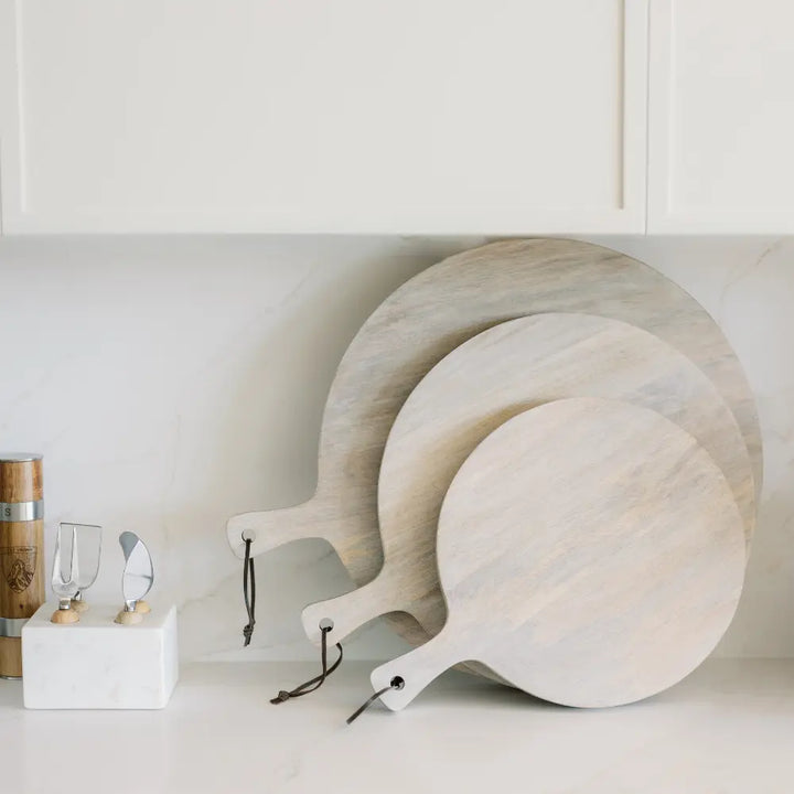 Round wooden serving boards with handles, styled beside glassware