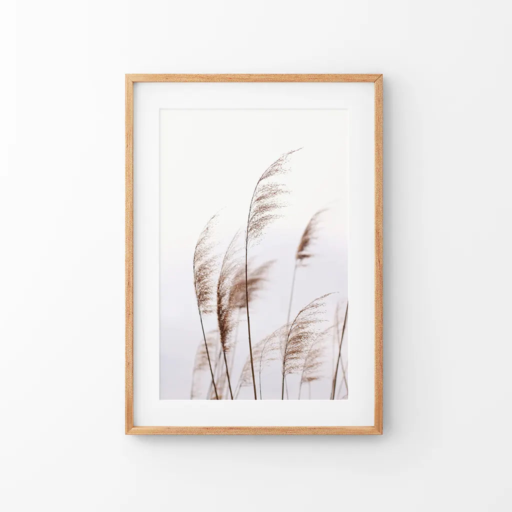 Beige dried grass print in a thin oak frame with mat, hung above a neutral console