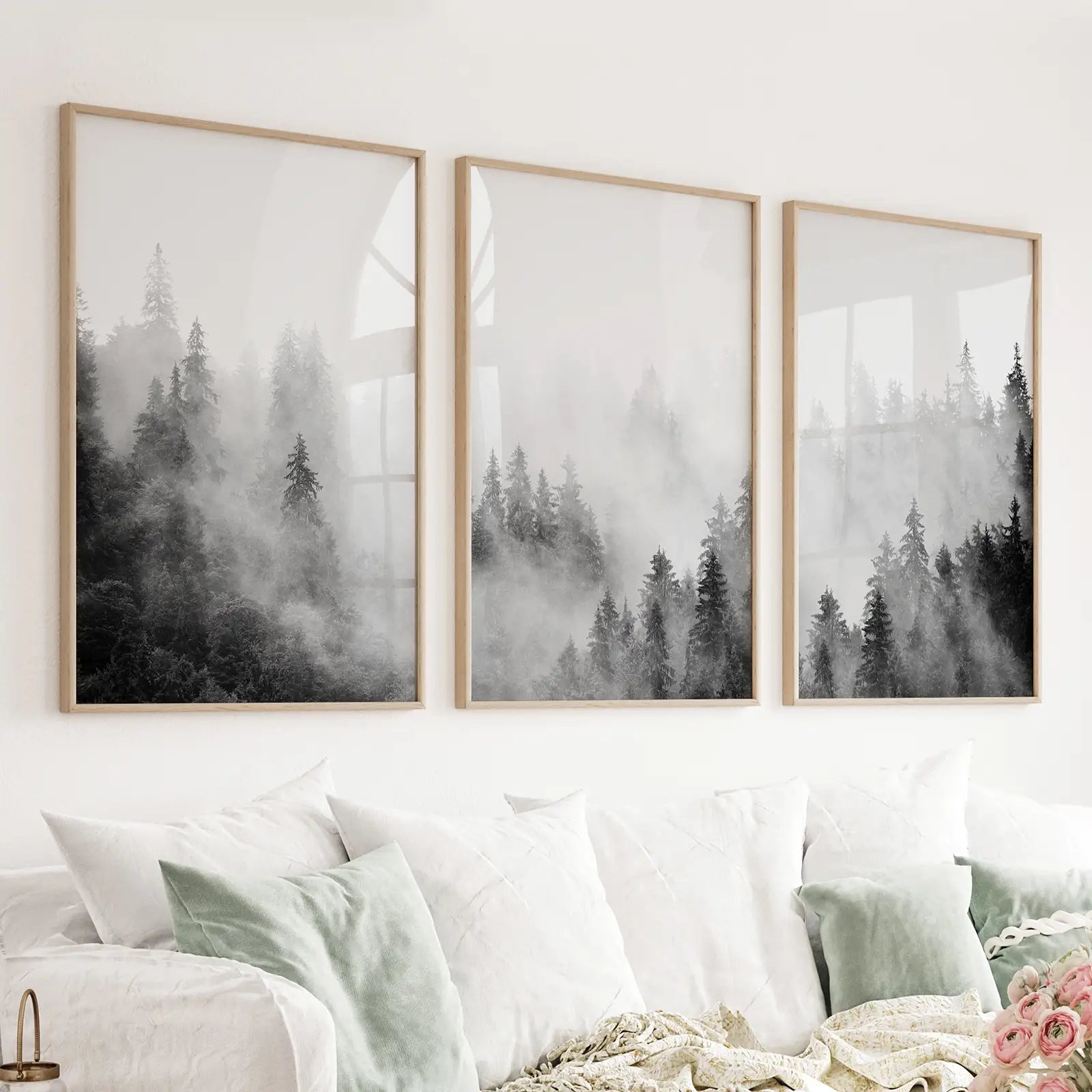 Black and white misty pine forest triptych in thin oak frames above a living room sofa