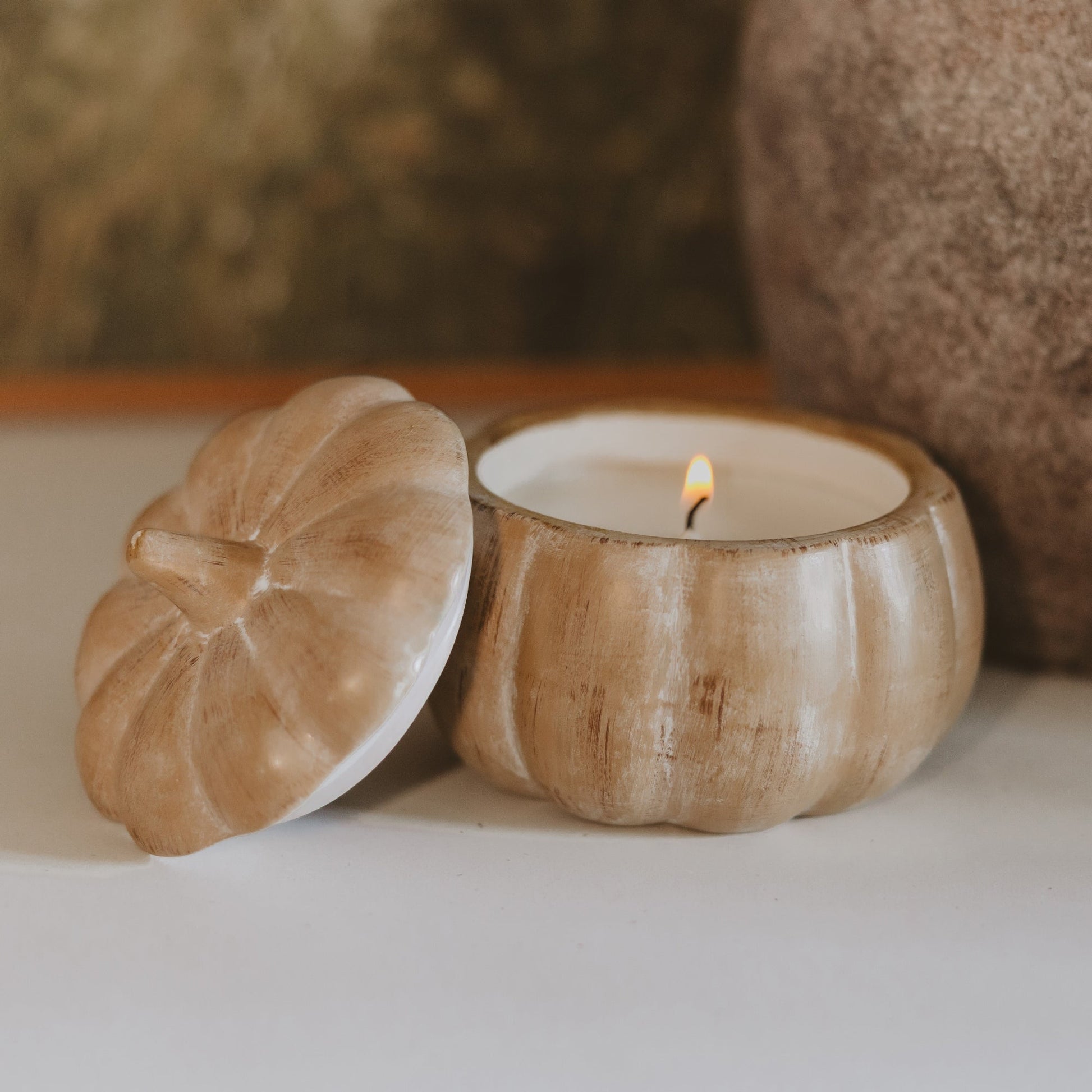 Lit pumpkin spice soy candle in a brushed tan ceramic pumpkin jar with lid alongside
