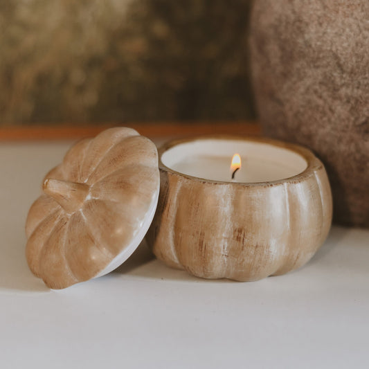 Lit pumpkin spice soy candle in a brushed tan ceramic pumpkin jar with lid alongside