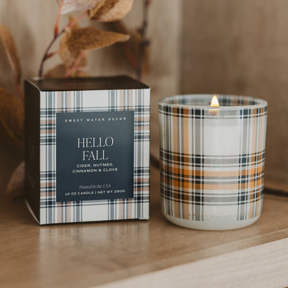 Lit Hello Fall soy candle in autumn plaid glass beside its matching plaid box
