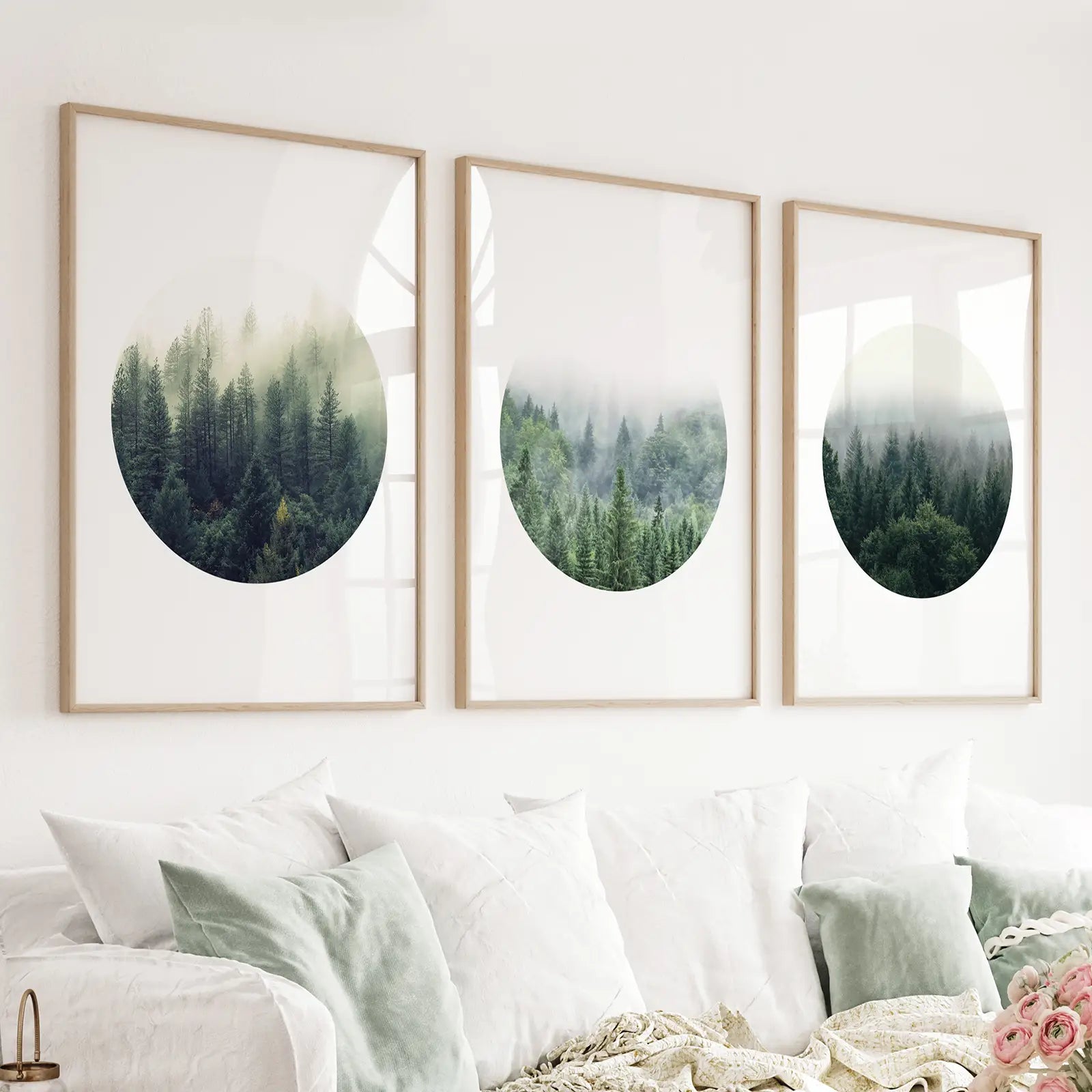 Set of three misty forest circle prints in wood frames above a light sofa