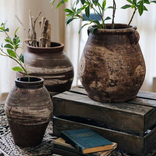 Weathered brown restoration clay pots styled with greenery on wooden crates