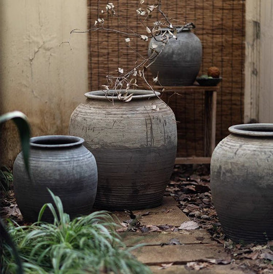 Large antique ceramic pots with weathered gray patina grouped in a courtyard
