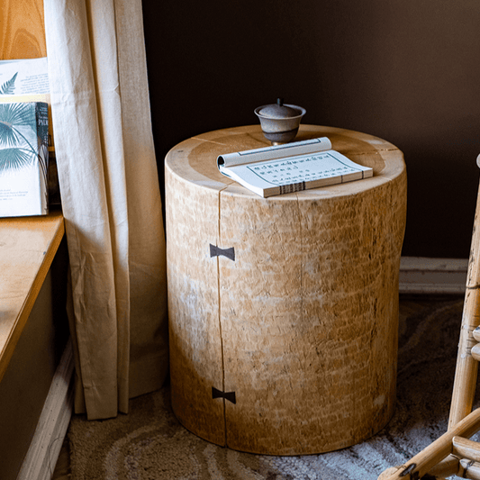 Pine log pedestal side table with butterfly joints beside a curtained window