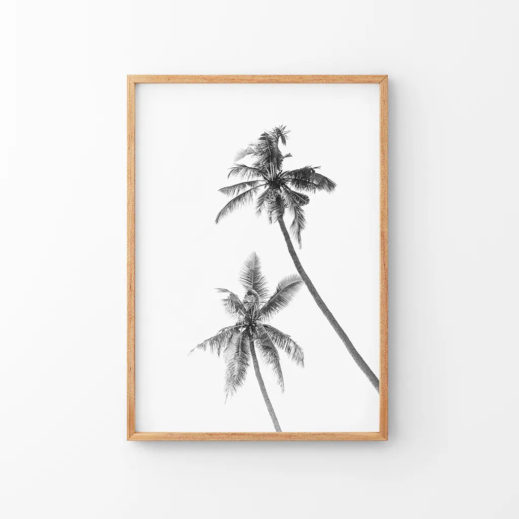 Black and white palm trees print in a thin wood frame on a white wall