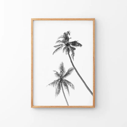 Black and white palm trees print in a thin wood frame on a white wall
