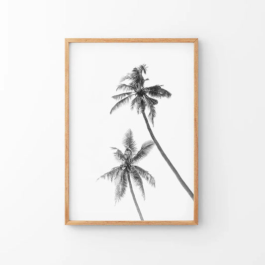 Black and white palm trees print in a thin wood frame on a white wall