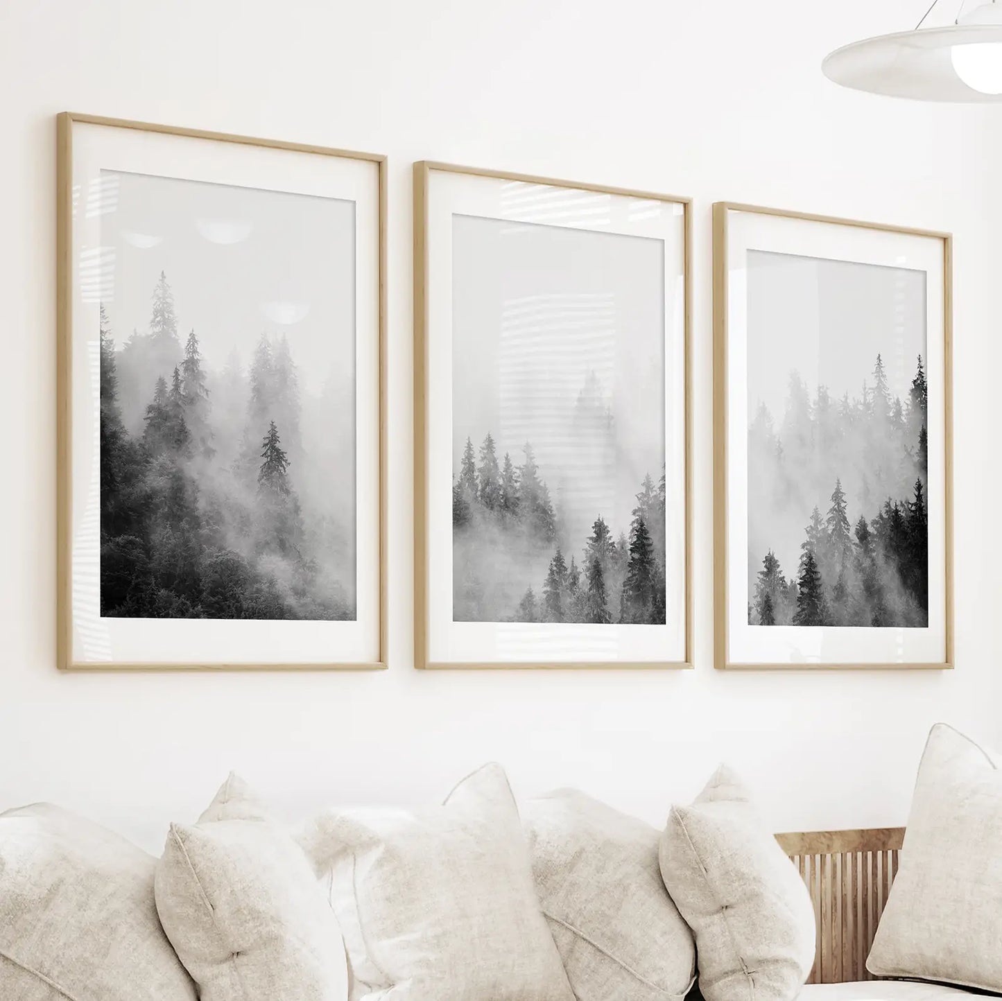 Set of three foggy forest prints, matted in thin oak frames above a couch