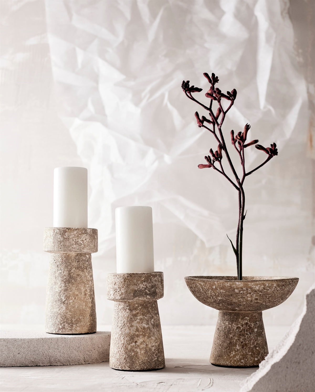 Textured pedestal bowl and candleholders with a burgundy flower on a warm neutral table