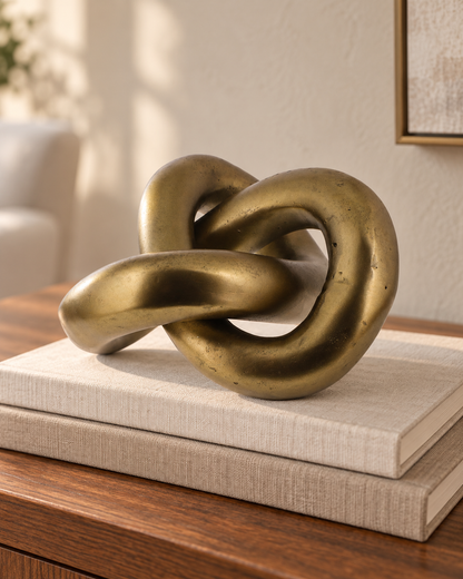 Infinity Knot — Brass styled on linen-covered books on a wood console