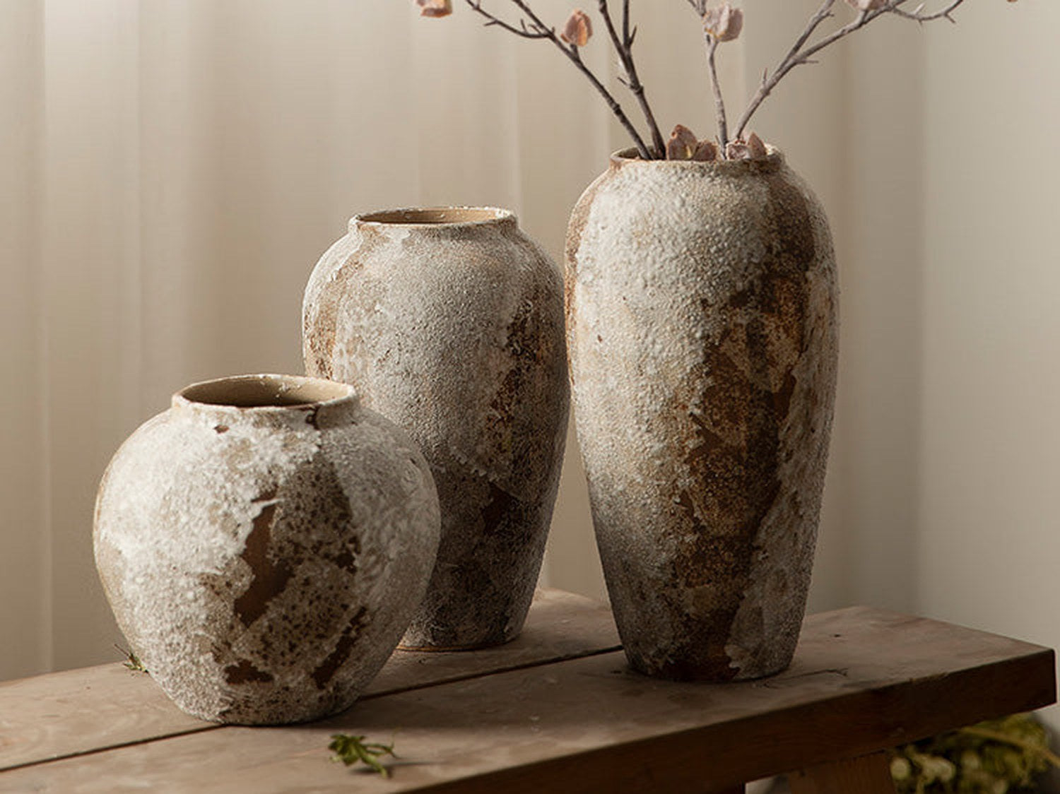 Rustic ceramic vases with dried botanicals on a wood bench — editorial